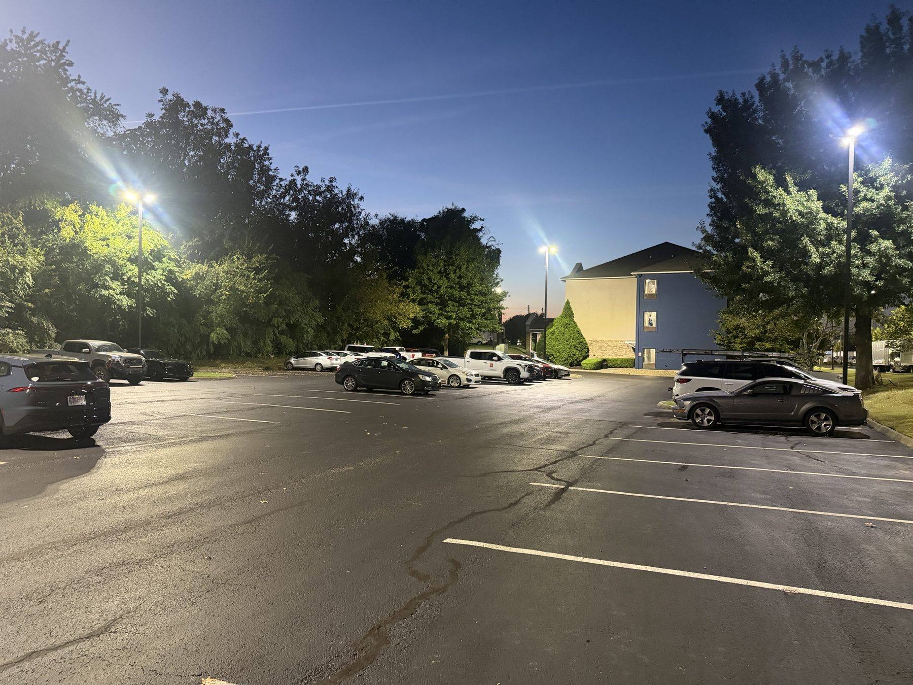 The parking lot at Knoxville Park and Fly at dusk, with marked spaces and lot lighting